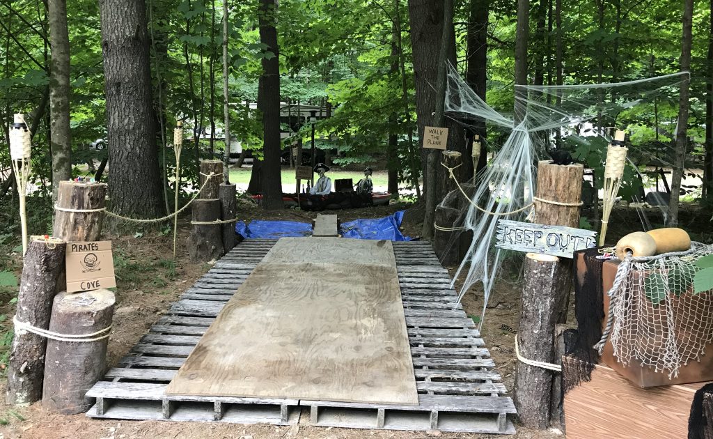 DIY pirate-themed Halloween walk-the-plank trail made from pallets, logs, rope, and Halloween decorations.