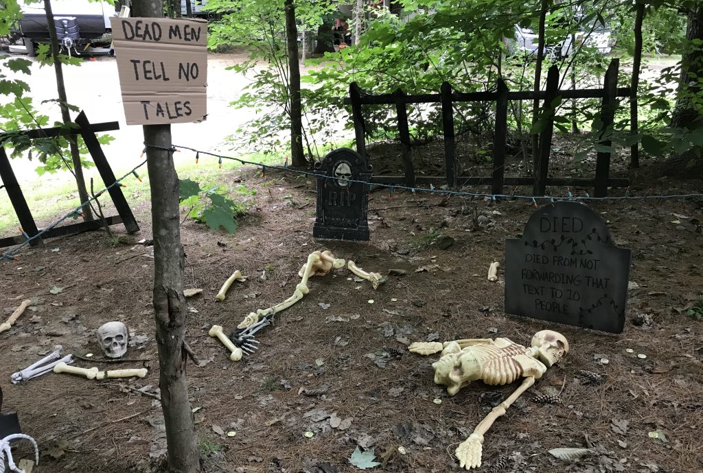 DIY pirate graveyard Halloween display with skeletons, tombstones, and a "Dead Men Tell No Tales" pirate sign.