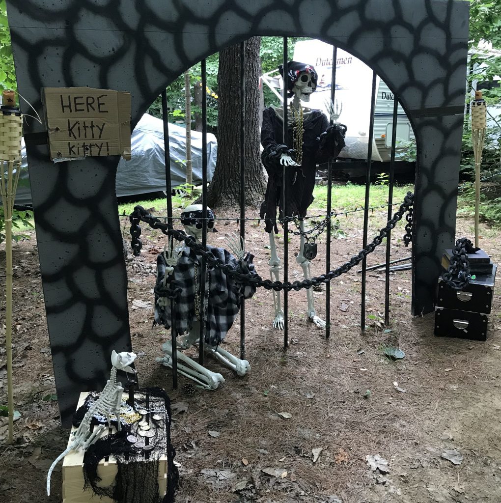 DIY pirate jail Halloween scene with skeleton prisoners behind PVC jail bars and painted foam stone walls.