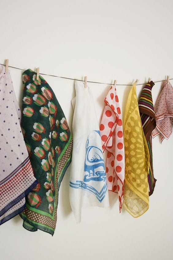 scarves hanging from a clothes line on a wall