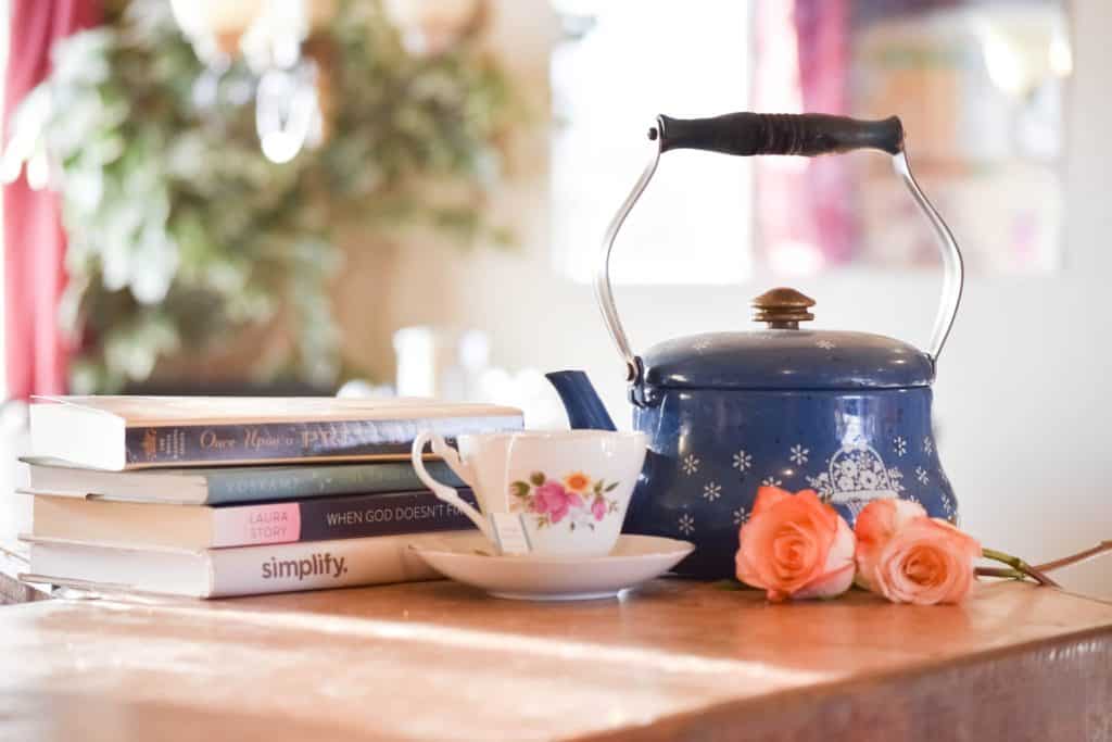 blue tea kettle with tea cup on a table with books